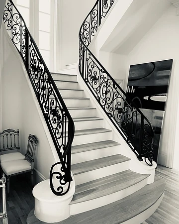 Black and white view of the ornamental curved iron stair railing and its scrollwork pattern