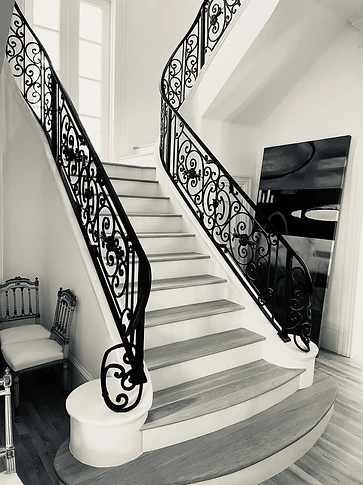Black and white view of the ornamental curved iron stair railing and its scrollwork pattern
