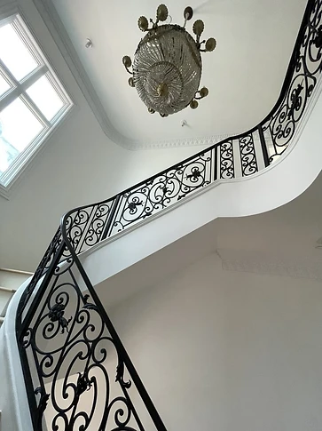 Upward view of the ornamental iron railing following the curved stair through multiple levels