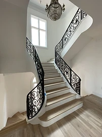 Multi-level ornamental curved iron stair railing in a grand residential interior