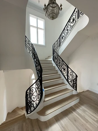 Multi-level ornamental curved iron stair railing in a grand residential interior