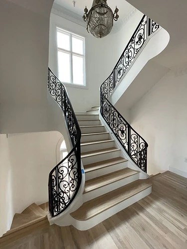 Multi-level ornamental curved iron stair railing in a grand residential interior