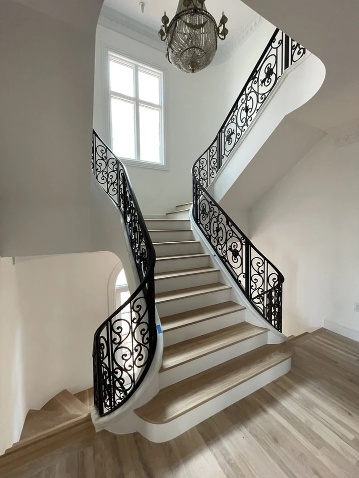 Multi-level ornamental curved iron stair railing in a grand residential interior