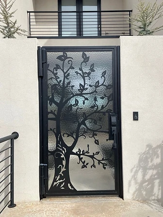 Pedestrian gate with decorative metal tree silhouette and textured privacy glass