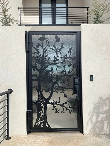 Pedestrian gate with decorative metal tree silhouette and textured privacy glass