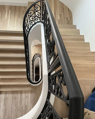 Close view of the shaped handrail and ornamental scrollwork detail on the curved stair railing