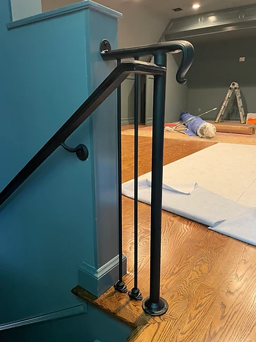 Wall-mounted handrail turning the corner at the stair landing with scrolled termination