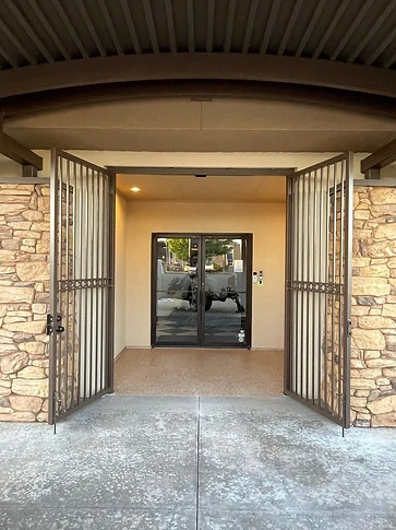The double entry gate standing open beneath a stone archway entry