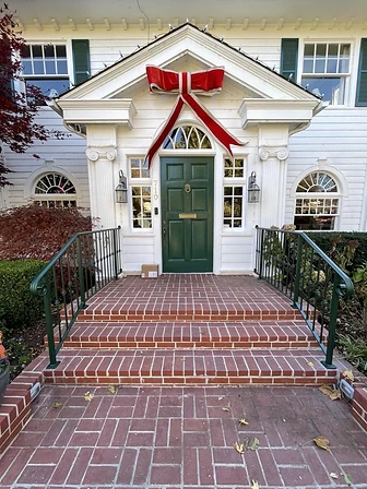 Custom green exterior iron entry railings at a residential front entrance