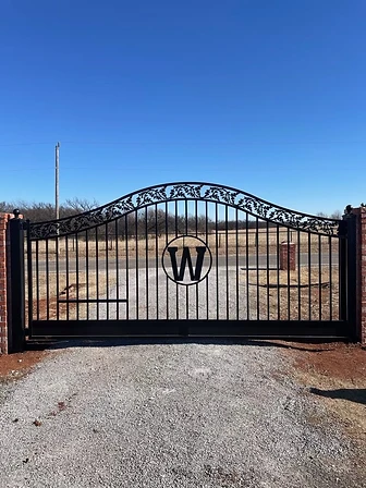 Ornamental estate driveway gate with custom monogram detail