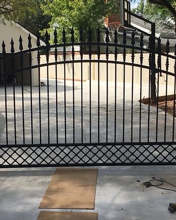 Arched ornamental estate gate with spear-point finials and lower lattice detail during installation