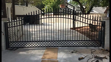 Arched ornamental estate gate with spear-point finials and lower lattice detail during installation