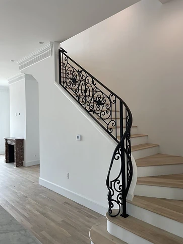 Ornamental curved iron stair railing rising through a residential foyer