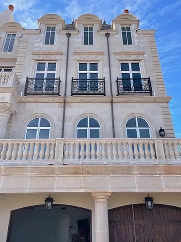 Three matching ornamental Juliet-style iron balcony guards on a residential facade