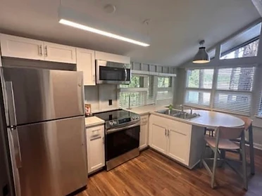 Modern cabin kitchen with white Shaker cabinets, stainless appliances, and wood-look flooring