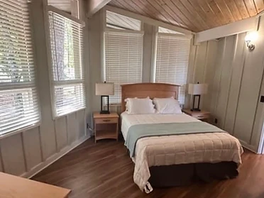Cabin bedroom with natural wood headboard and vaulted wood beam ceiling