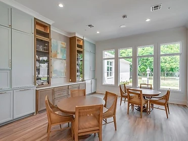 Multi-purpose room with blue-gray cabinetry and round tables