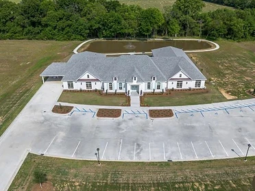Aerial site view of The Oaks with retention pond and parking