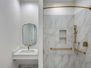 Accessible bathroom with gold fixtures and marble shower