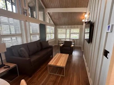 Cabin living area with charcoal sofa, wood coffee table, and vaulted wood ceiling