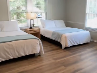 Renovated cabin bedroom with two queen beds and vaulted wood-plank ceiling
