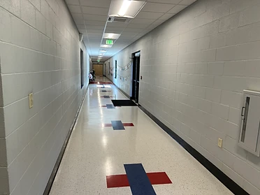 Interior hallway with VCT flooring and red and blue accent tiles at Ackerman Elementary Addition