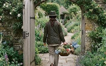 A gardener walking through a gate into an established English garden