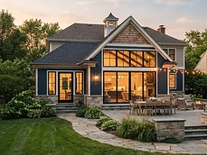 Completed Home Additions with blue siding, stone base, and patio lighting at dusk in Holmdel, NJ.