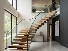 Floating wooden stairs and frameless glass railing system featured in a modern interior in Avon-by-the-Sea, NJ.