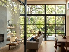 Interior view of large black steel Doors & Windows overlooking a lush garden in Deal, NJ residence.