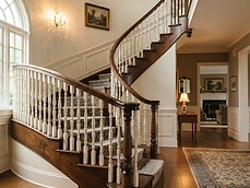 Classic wooden staircase with decorative white spindles and carpeted treads in a home in Deal, NJ.