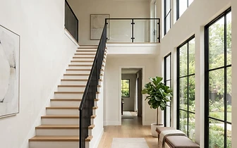 Modern interior foyer featuring wooden stairs and black metal railing in a home in Holmdel, NJ.