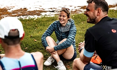 Athletes resting on a hill overlooking the water at a gravel triathlon