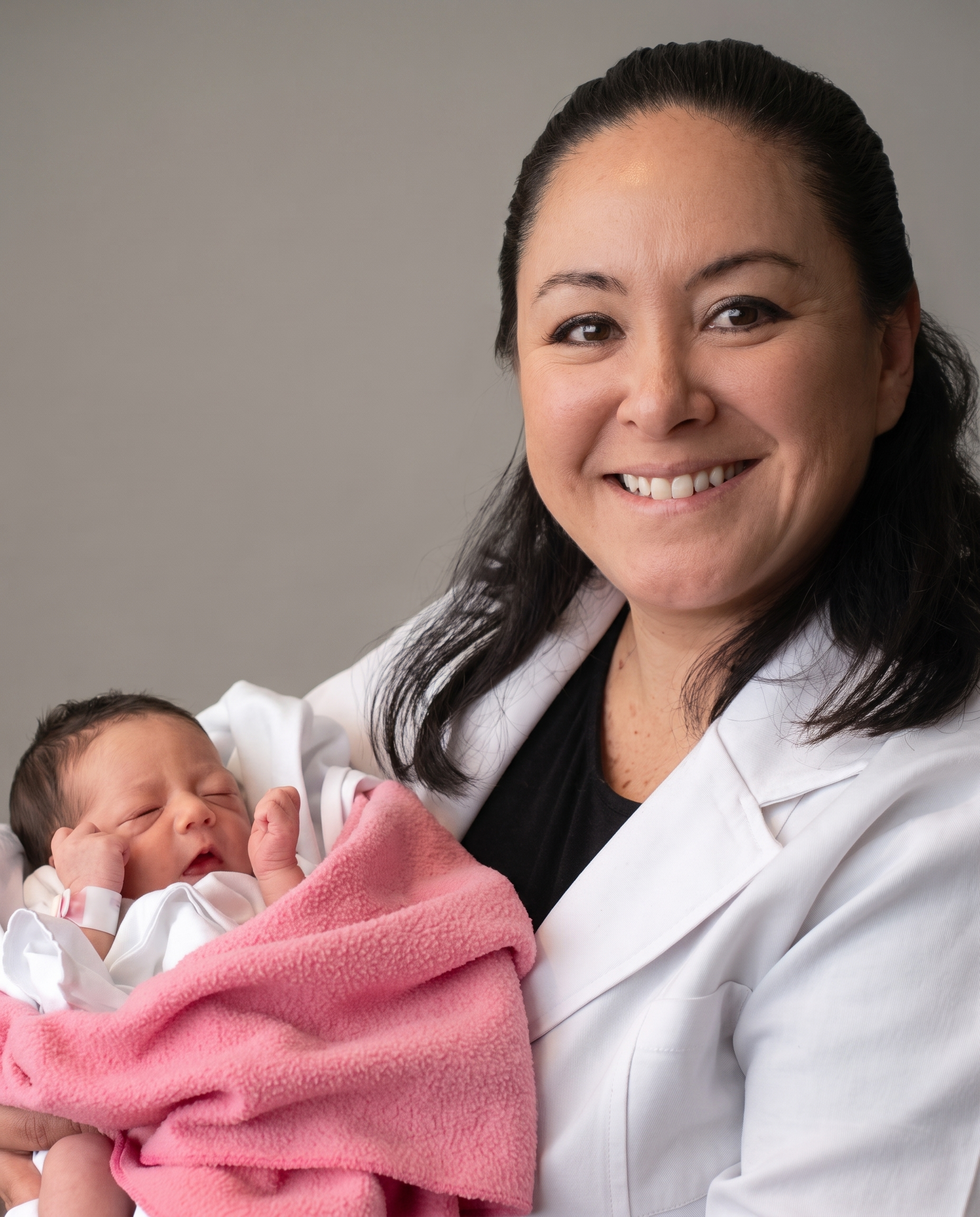 Dra. Luz con bata blanca sosteniendo a un bebé