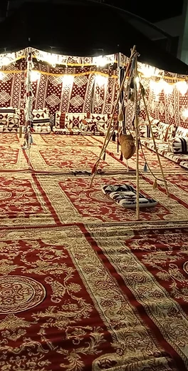 خيمة عربية ليلية مضاءة بالمصابيح مع سجاد تراثي وأجواء تراث أصيل