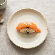 Fresh salmon nigiri on a cream plate