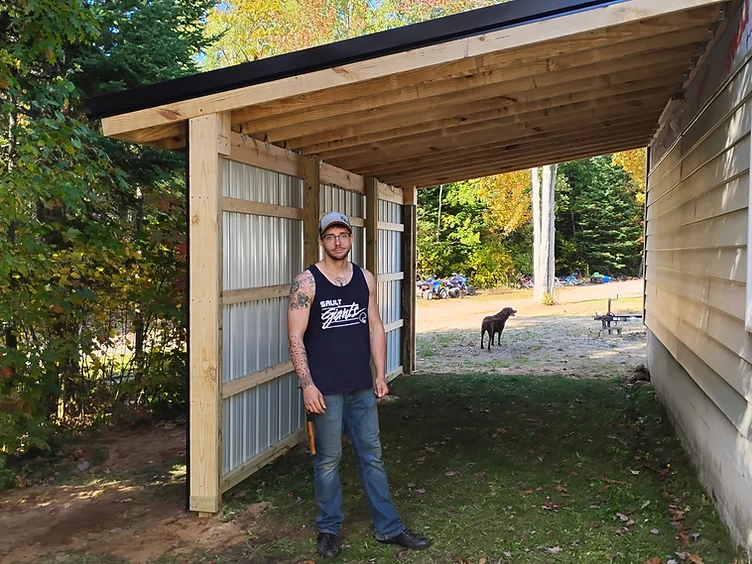 Kody Matthews, owner of All Aspects, standing in front of a lean to he build in Sault Ste. Marie, Michigan