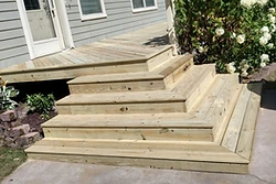 New wrap-around pressure-treated deck and stairs with mitered corners built by All Aspects