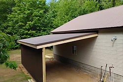 Newly constructed brown metal carport lean-to with pressure-treated lumber framing built by All Aspects