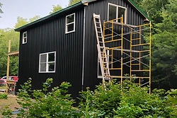 Two-story building under construction with metal siding and a green roof by All Aspects