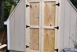 Newly built plywood double shed doors with black T-hinges by All Aspects
