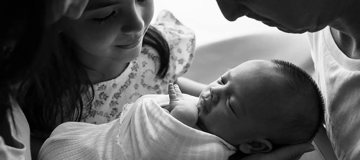 Family holding a newborn, symbolising wealth across generations
