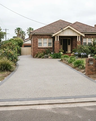 Textured resurfaced driveway with a darker border at an older brick home