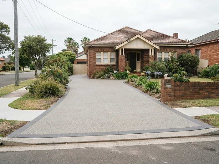 Textured resurfaced driveway with a darker border at an older brick home