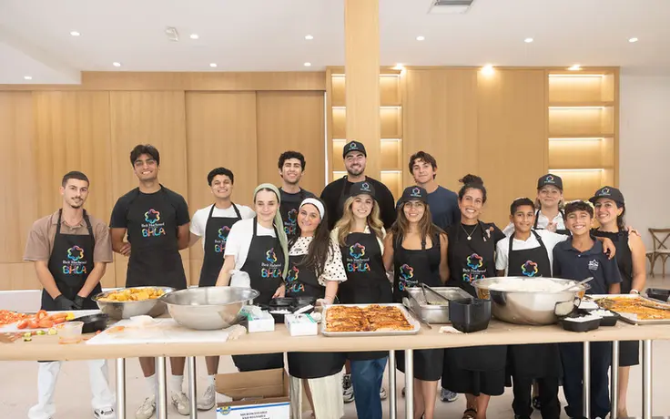 A large group of Beit Hachesed Kitchen volunteers at the prep table