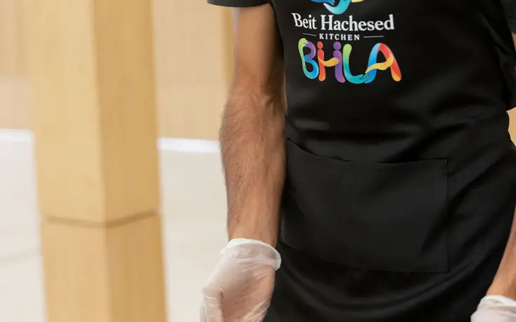 A volunteer holding a tray of prepared fish in the Beit Hachesed Kitchen