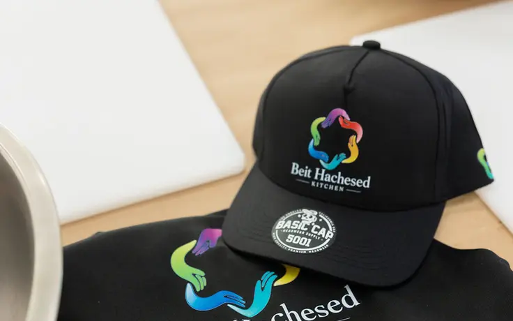 Branded Beit Hachesed Kitchen cap and apron on the prep table