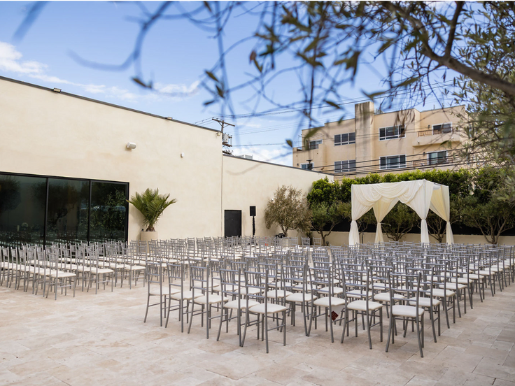 Outdoor wedding ceremony beneath a white chuppah