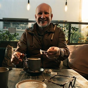 Bernard Faulhammer seated at a cafe table with a coffee
