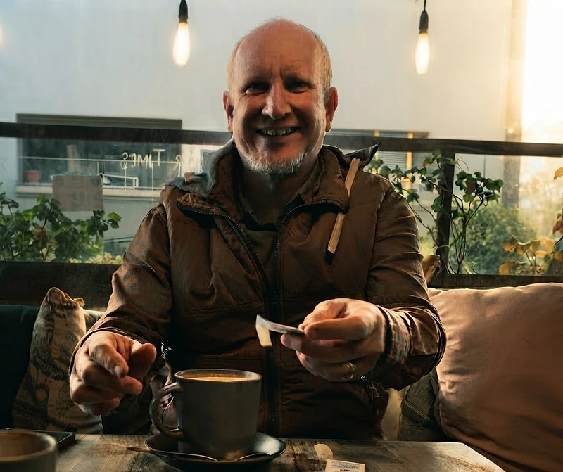 Bernard Faulhammer seated at a cafe table with a coffee